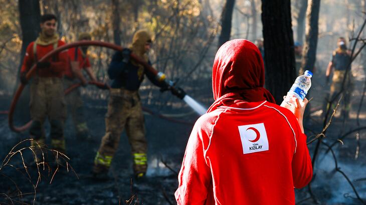 A Turkish Red Crescent volunteer provides water to firefighting teams responding to wildfires across Türkiye in July 2025. The Red Crescent is supporting both emergency responders and affected residents with essential supplies and relief services. 